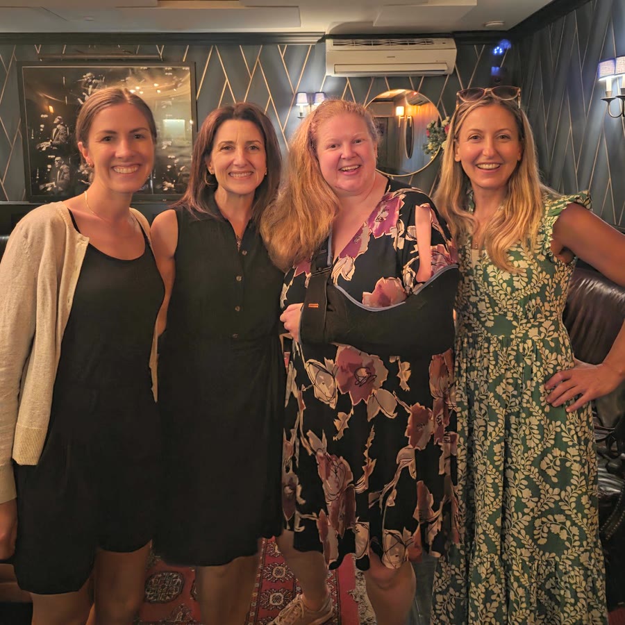 Nicole and three lab colleagues smiling together at an evening get-together