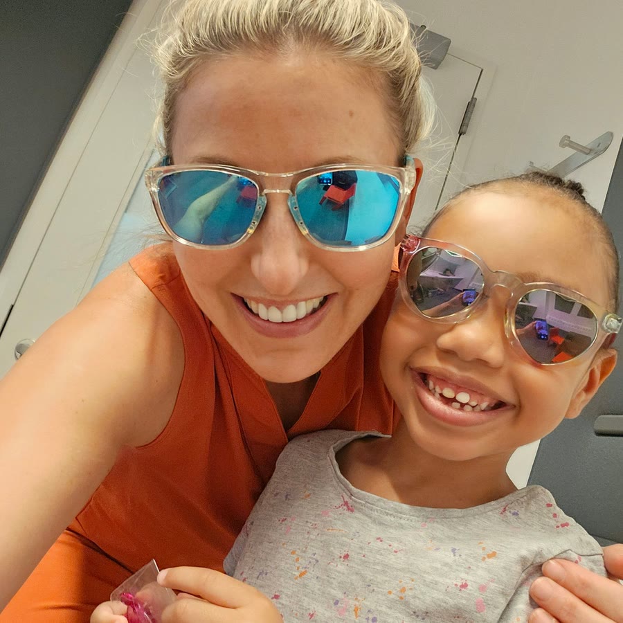 Nicole and a smiling little girl posing together in sunglasses
