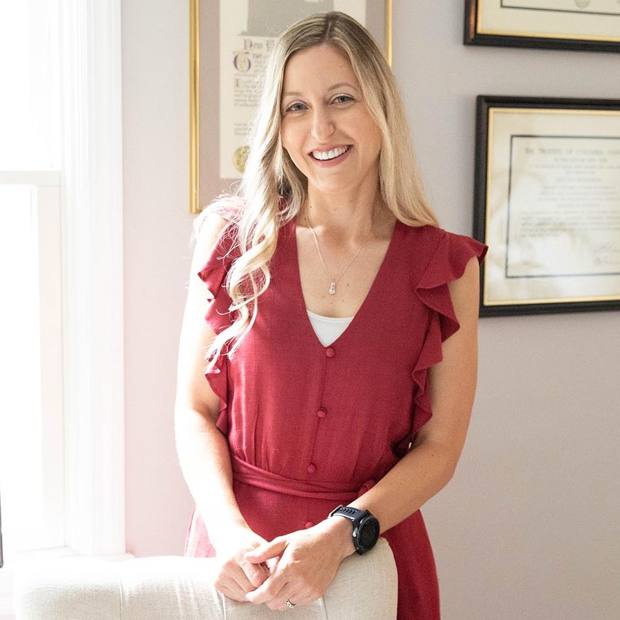 Nicole smiling in her office in a red dress