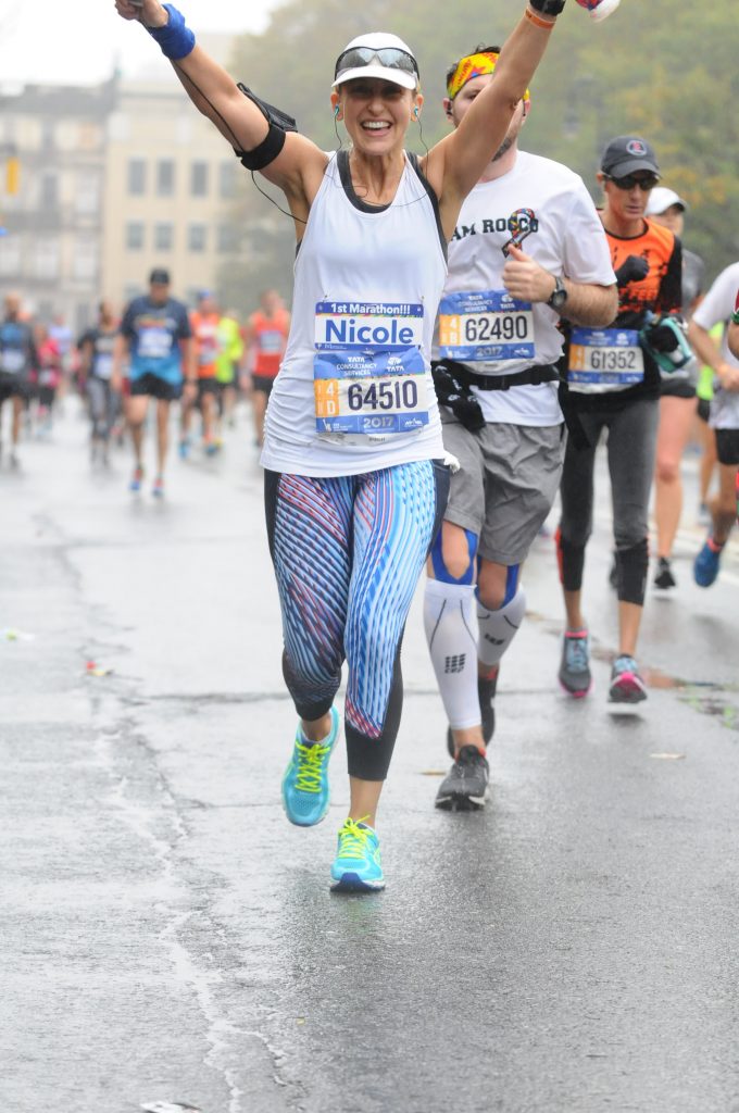 Nicole running the 2017 New York City Marathon, arms raised